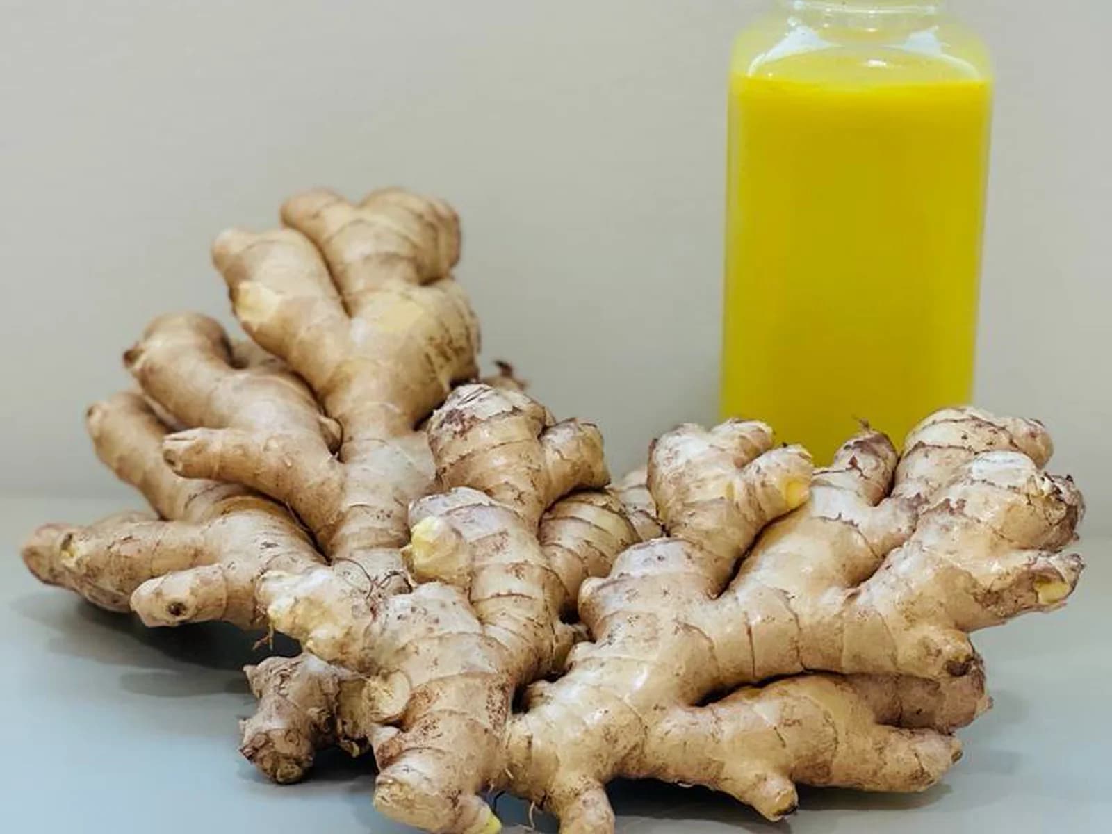 Fresh ginger roots presented with ginger juice.