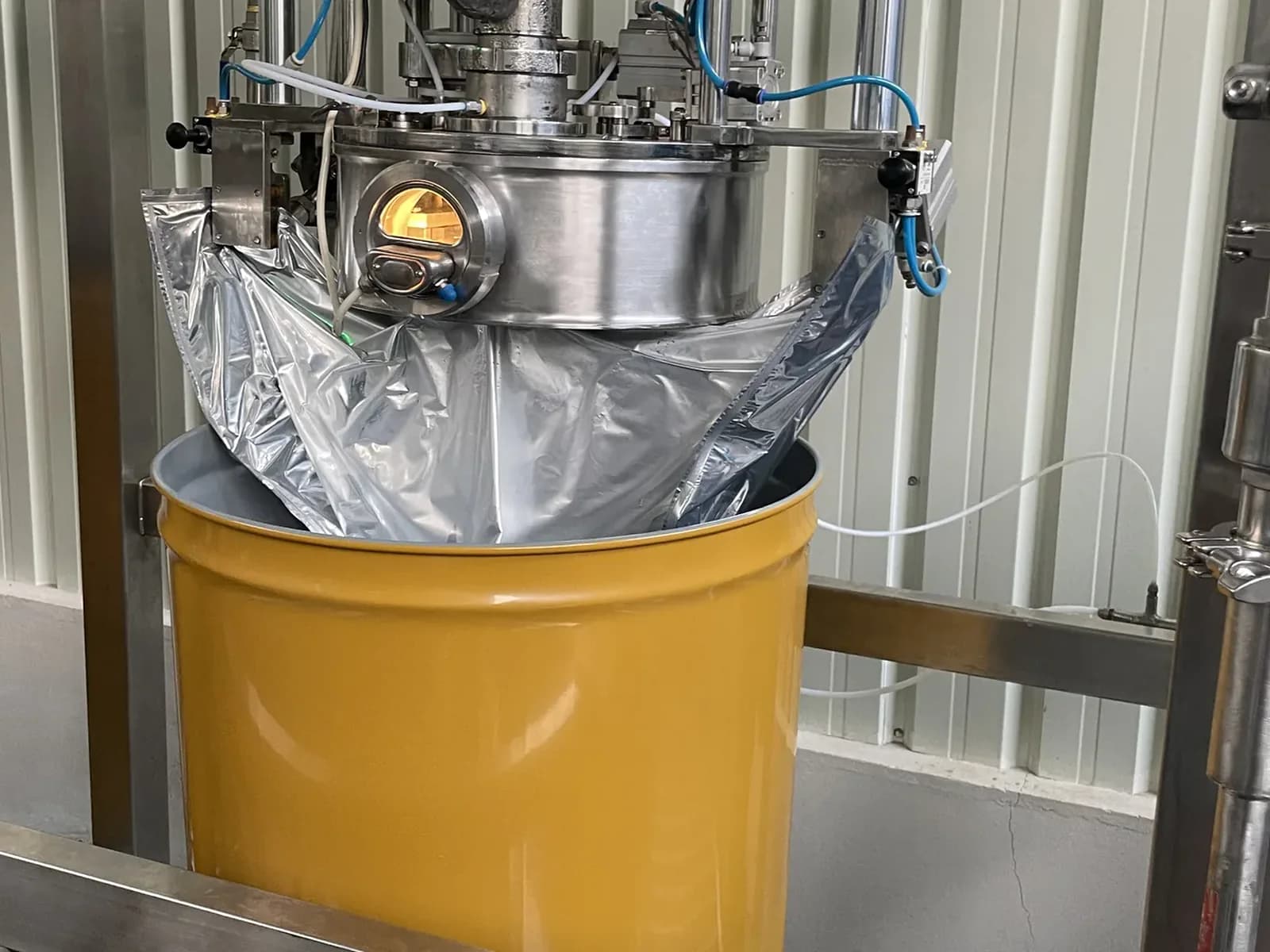 Orange juice being filled into a commercial drum.