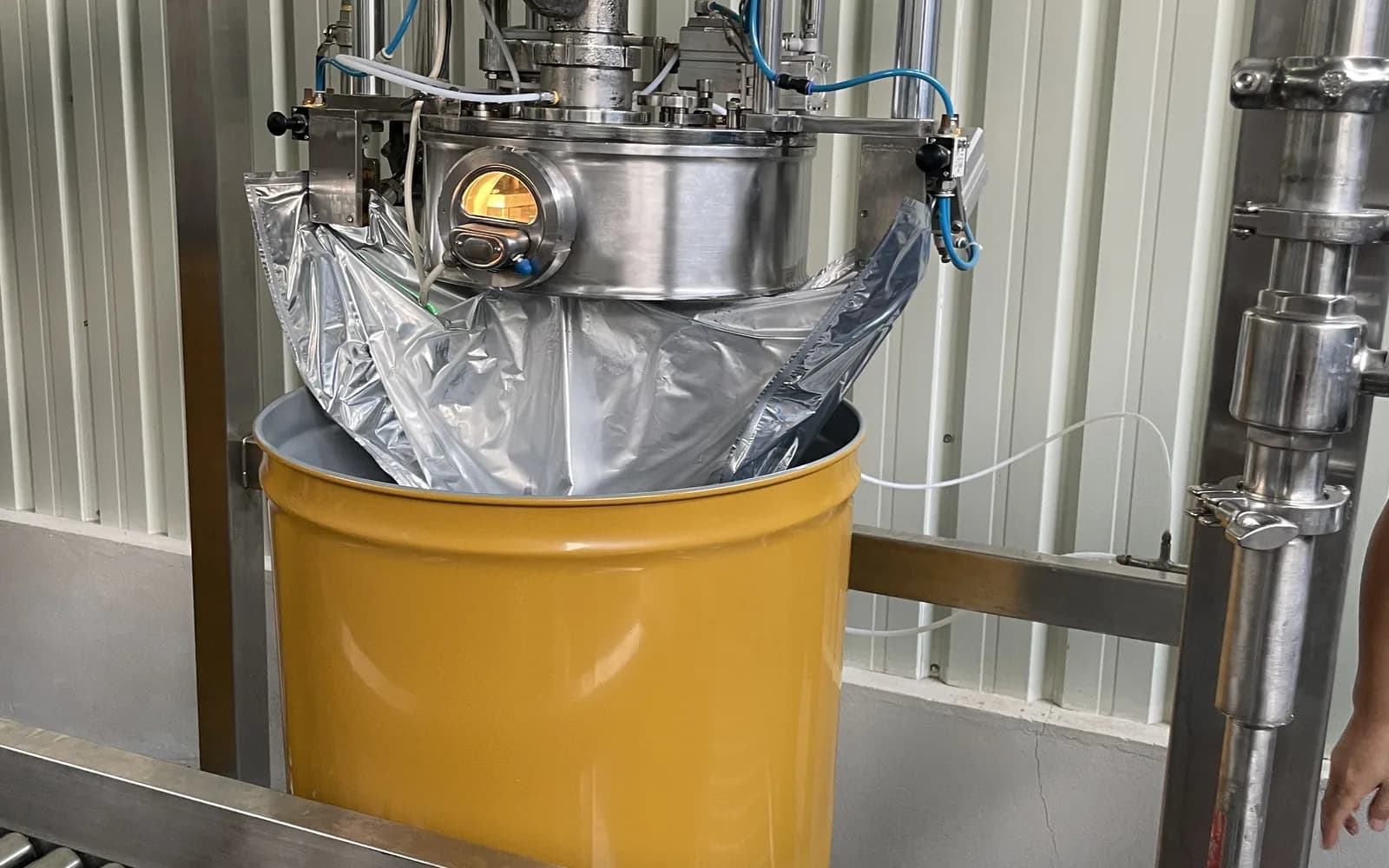Orange juice being filled into a commercial drum.